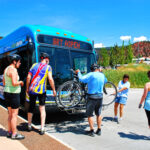 Man lifting bike to load on front of bus