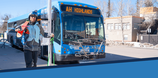 A image of a RFTA bus with a skier walking in front with a pair of skis